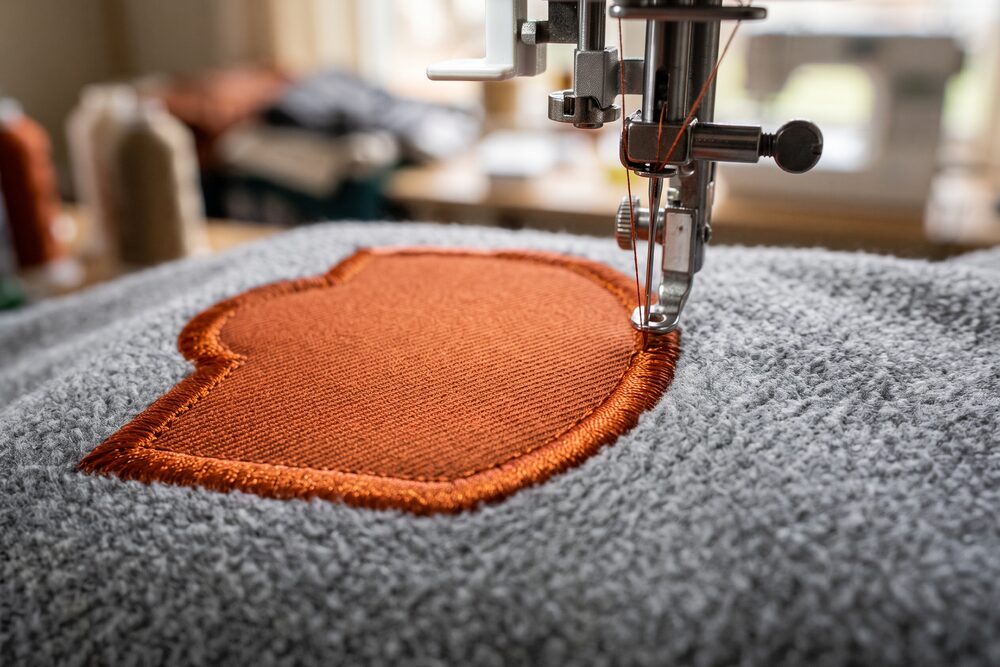 An orange twill patch satin-stitched onto grey fleece
