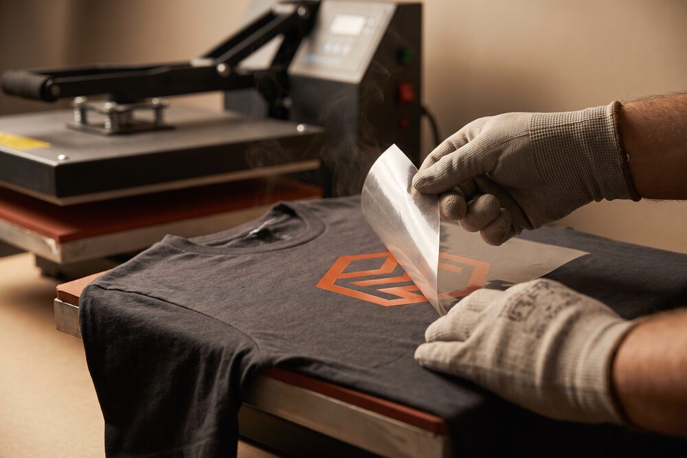 A transfer carrier sheet peeled back from a garment, revealing the bonded mark